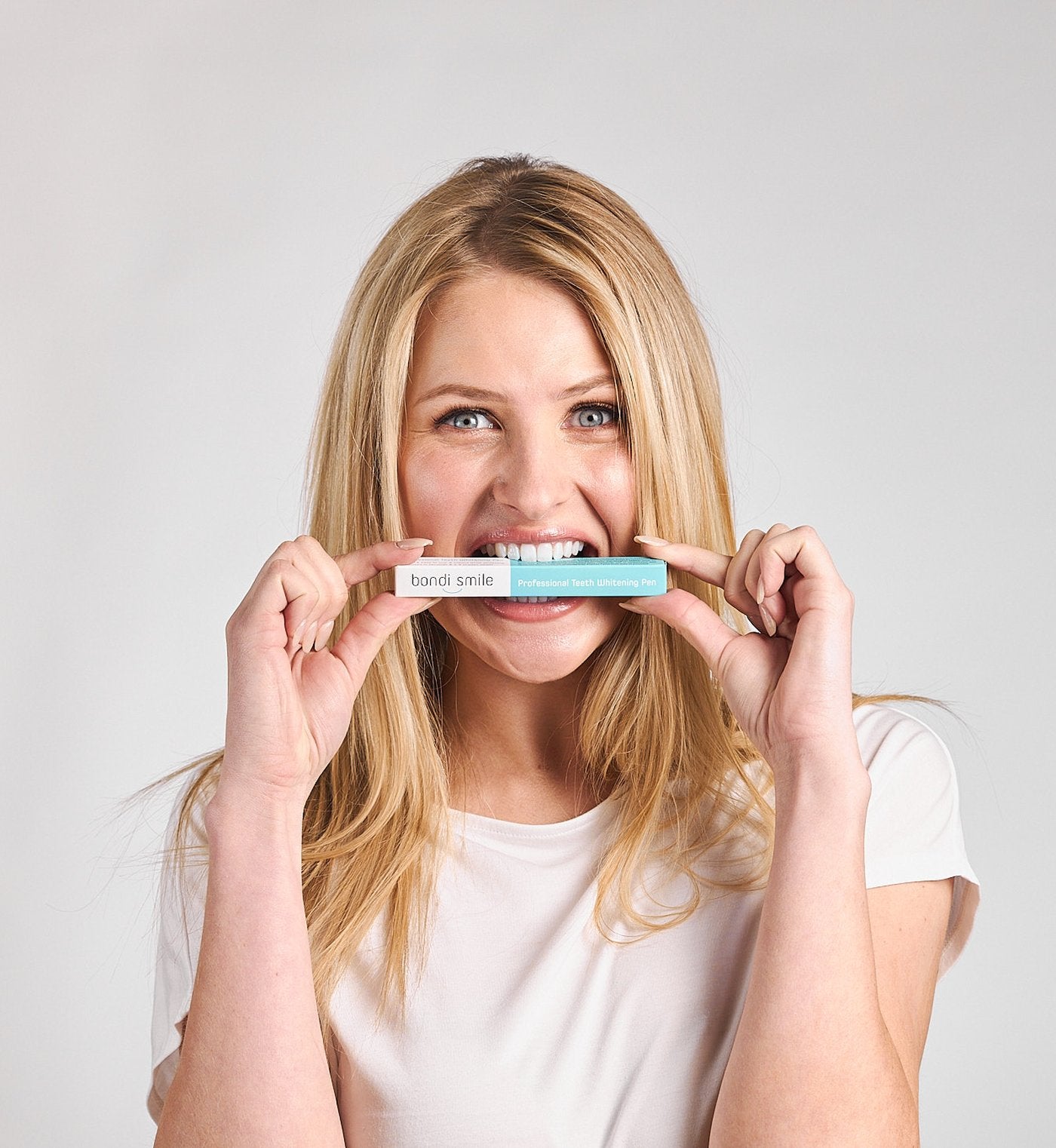 Smiling woman holding a Bondi Smile Professional Teeth Whitening Pen at her teeth